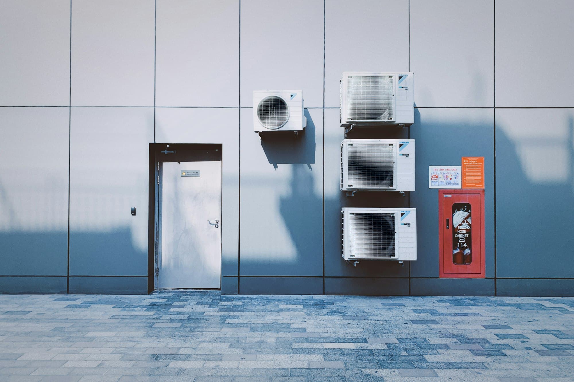 Quatre unités extérieures fixées sur la façade grise d'un bâtiment commercial